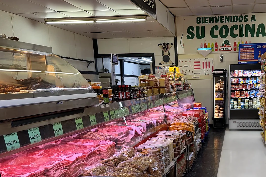 El mostrador de la carnicería con carne fresca en la vitrina, bajo el letrero Bienvenidos a su cocina